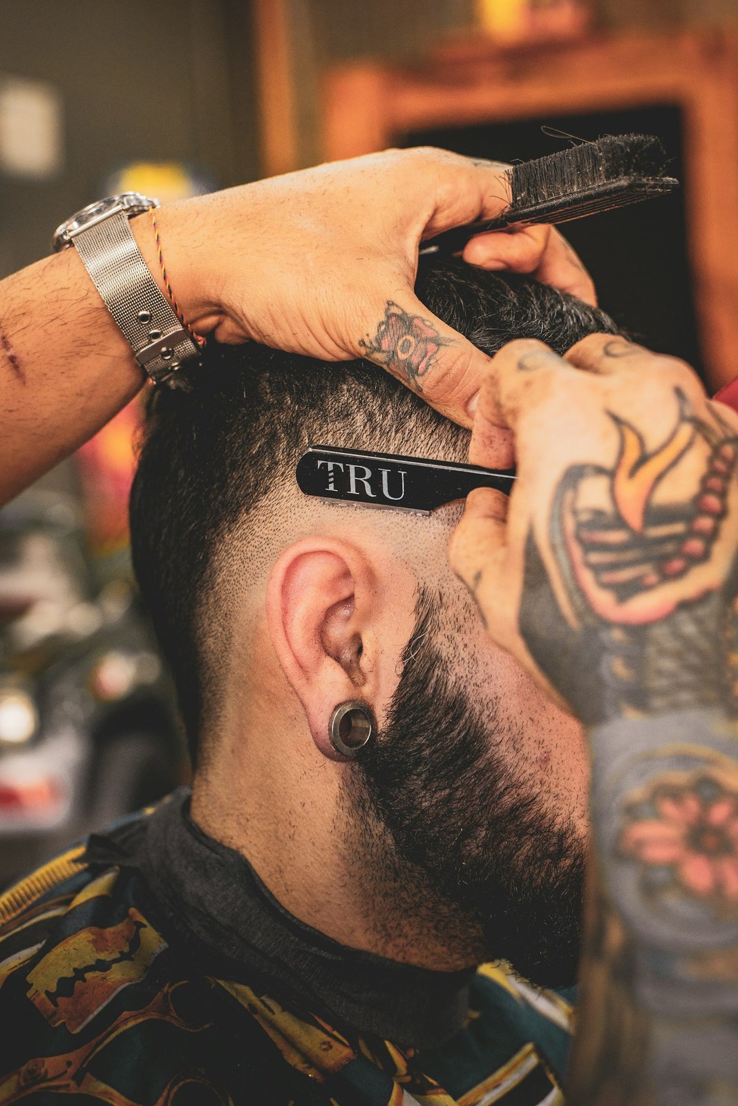 Close-up of a barber using a straight razor on a fade — illustrative photo, not this English Market unit